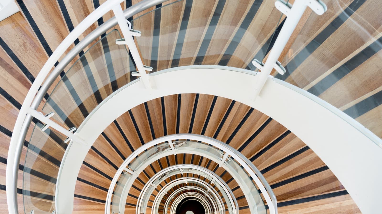 A spiral staircase made of timber with white metal beams