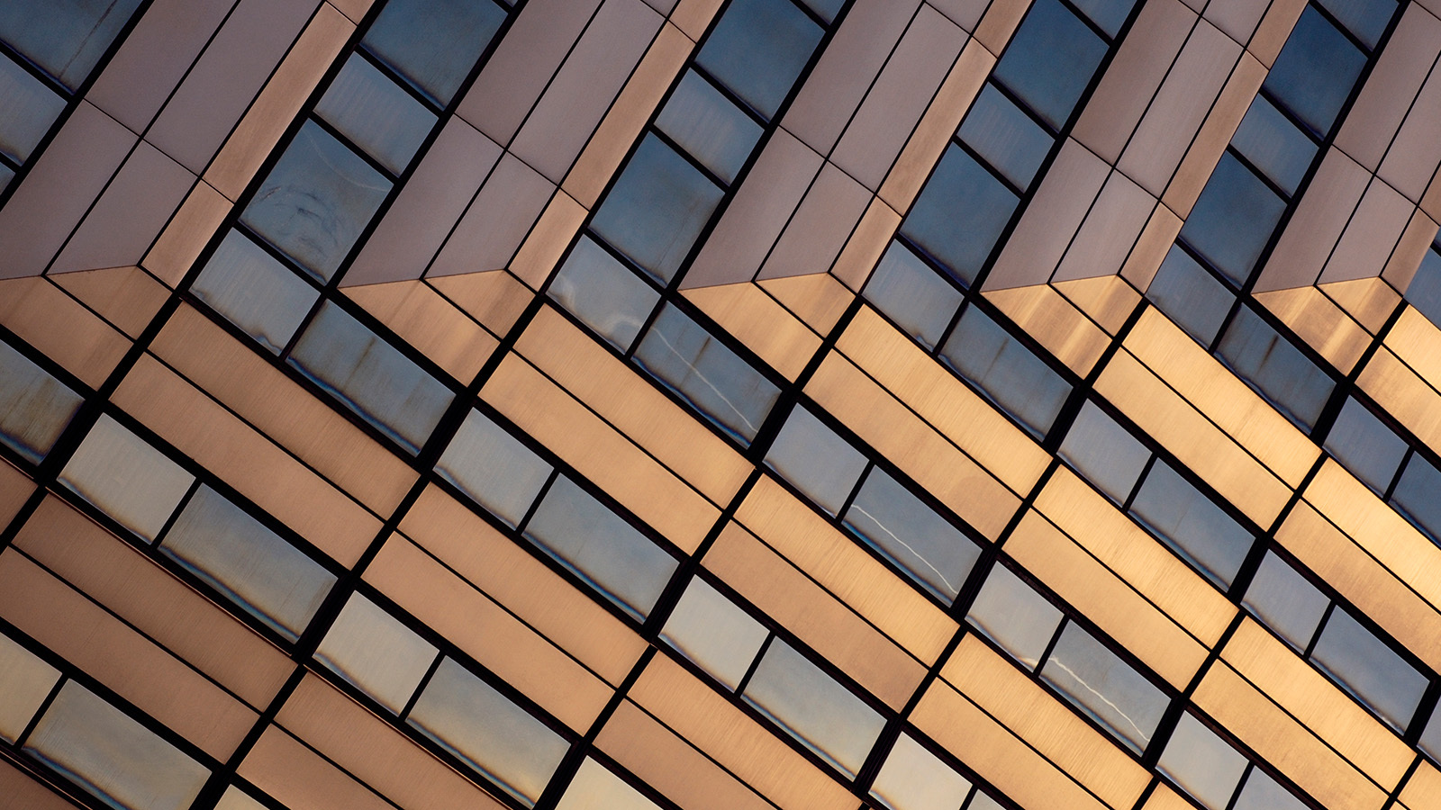 Modern office building, orange-grey coloured, reflecting sunshine.
