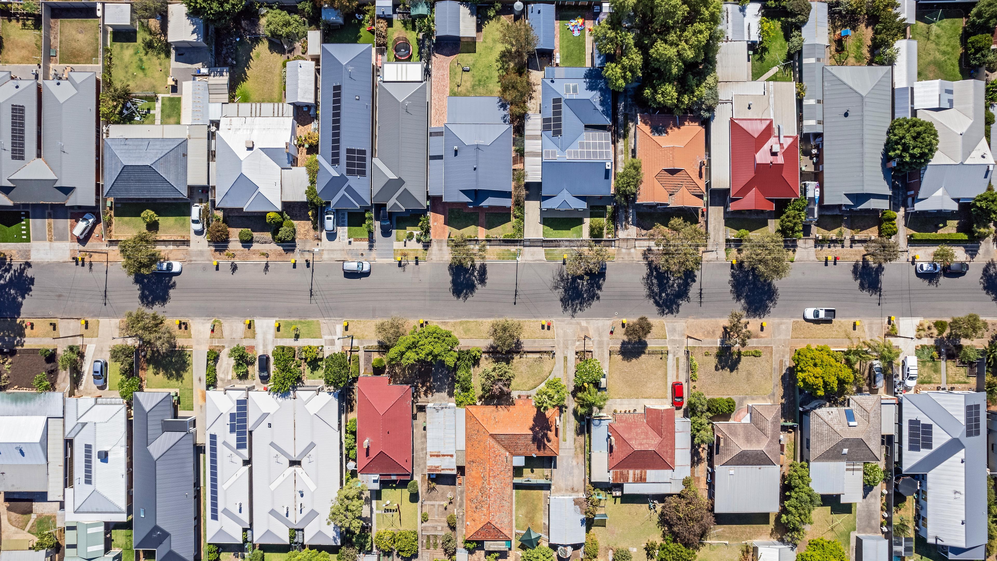 Aerial view of established houses on either side of a street in an Australian suburb.